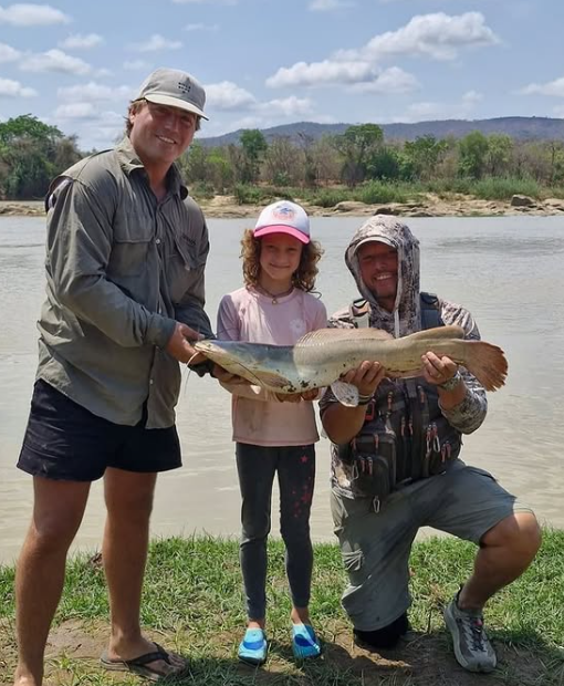 Travelers with a fresh catch on the Rufiji River during a Uwanda boat safari.