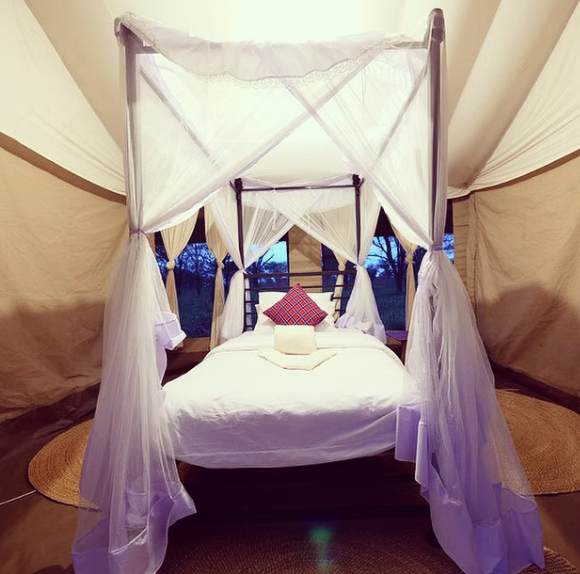 Luxury safari tented suite bed with mosquito netting and evening bush light at Osero Tented Camp.